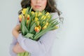 Beautiful young woman with curly hair holds a bouquet of tulips. Women`s Day. Spring Royalty Free Stock Photo