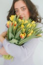 Beautiful young woman with curly hair holds a bouquet of tulips. Women`s Day. Spring Royalty Free Stock Photo