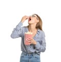 Beautiful young woman with 3D cinema glasses eating popcorn on white background Royalty Free Stock Photo