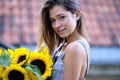 Beautiful young woman with dark hair in a hat, in the city, holding hands for a bouquet of sunflowers and looking away. Royalty Free Stock Photo