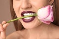 Beautiful young woman with dark lipstick and flower in mouth, closeup Royalty Free Stock Photo