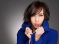 Beautiful young woman deep in thoughts. Wearing dark blue winter coat. Studio portrait.