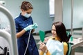 The beautiful young woman is at the dentist. She sits in the dentist`s chair and the dentist carefully examines the patient`s