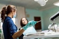 The beautiful young woman is at the dentist. She sits in the dentist`s chair and the dentist carefully examines the patient`s