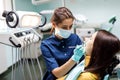 The beautiful young woman is at the dentist. She sits in the dentist`s chair and the dentist carefully examines the patient`s