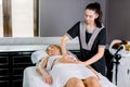 Beautiful young woman doctor massage therapist in a cosmetology room doing an abdomen massage to young blond woman Royalty Free Stock Photo