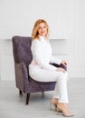 Beautiful young woman doctor in white uniform posing in a chair and looking at the camera Royalty Free Stock Photo