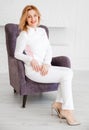 Beautiful young woman doctor in white uniform posing in a chair and looking at the camera Royalty Free Stock Photo