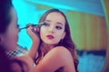 A beautiful young woman is doing herself a makeover. Girl with cerly hair doing evening makeup using brush and eyeshadow i Royalty Free Stock Photo