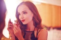 A beautiful young woman is doing herself a makeover. Girl with cerly hair doing evening makeup using lipstick in front of mirror i Royalty Free Stock Photo