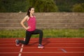 Beautiful young woman doing longe step on athletic track Royalty Free Stock Photo