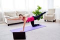 Beautiful young woman doing stretching exercise on floor at home, online training on laptop computer, copy space. Royalty Free Stock Photo