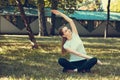 Beautiful young woman doing stretching exercise on green grass at park. Yoga workout Royalty Free Stock Photo