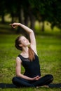 Beautiful young woman doing stretching exercise on green grass at park. Yoga workout Royalty Free Stock Photo