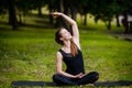 Beautiful young woman doing stretching exercise on green grass at park. Yoga workout Royalty Free Stock Photo
