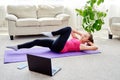 Beautiful young woman doing working out exercise on floor at home, online training on laptop computer, copy space. Royalty Free Stock Photo