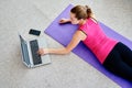 Beautiful young woman doing working out exercise on floor at home and using laptop, online training, copy space. Royalty Free Stock Photo