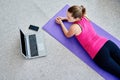 Beautiful young woman doing working out exercise on floor at home and using laptop, online training, copy space. Royalty Free Stock Photo