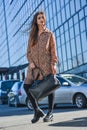 Beautiful young woman posing with a leather bag in a dress