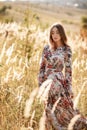 Beautiful young woman in dress in field at sunset. stylish romantic girl with long hair having fun outdoors Royalty Free Stock Photo