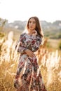 Beautiful young woman in dress in field at sunset. stylish romantic girl with long hair having fun outdoors Royalty Free Stock Photo