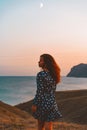 Beautiful young woman in a dress posing at dusk on Cape chameleon on the Black sea Royalty Free Stock Photo
