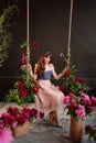 a beautiful young woman in a dress sits on a swing in peony flowers. Royalty Free Stock Photo