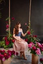 a beautiful young woman in a dress sits on a swing in peony flowers. Royalty Free Stock Photo