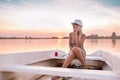 Beautiful young woman in a dress sitting on the boat and talking with her friend on mobile phone in a sunset Royalty Free Stock Photo