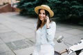 Beautiful young woman dressed casual sitting on scooter and talking on phone. Girl sitting on the bike and using Cellular smartpho Royalty Free Stock Photo