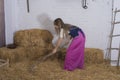 beautiful young woman, dressed in farmer outfit in barn with hay Royalty Free Stock Photo