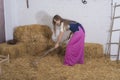 beautiful young woman, dressed in farmer outfit in barn with hay Royalty Free Stock Photo