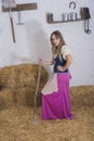 beautiful young woman, dressed in farmer outfit in barn with hay Royalty Free Stock Photo