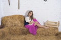 beautiful young woman, dressed in farmer outfit in barn with hay Royalty Free Stock Photo