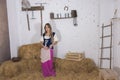 beautiful young woman, dressed in farmer outfit in barn with hay Royalty Free Stock Photo