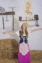 beautiful young woman, dressed in farmer outfit in barn with hay Royalty Free Stock Photo