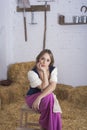 beautiful young woman, dressed in farmer outfit in barn with hay Royalty Free Stock Photo