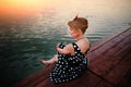 A beautiful young woman dressed sitting on the pier Royalty Free Stock Photo