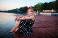 A beautiful young woman dressed sitting on the pier Royalty Free Stock Photo