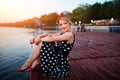 A beautiful young woman dressed sitting on the pier Royalty Free Stock Photo