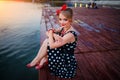 A beautiful young woman dressed sitting on the pier Royalty Free Stock Photo