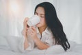 Beautiful young woman drinking coffee in bed.