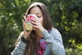 Beautiful young woman drinking coffee in a morning park Royalty Free Stock Photo