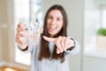 Beautiful young woman drinking a fresh glass of water very happy pointing with hand and finger Royalty Free Stock Photo