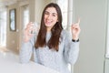 Beautiful young woman drinking a fresh glass of water very happy pointing with hand and finger to the side Royalty Free Stock Photo