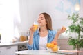 Beautiful young woman drinking fresh orange juice in kitchen Royalty Free Stock Photo