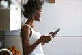 Beautiful young woman drinking green detox juice and using her mobile phone at home. Royalty Free Stock Photo