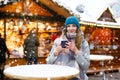 Beautiful young woman drinking hot punch, mulled wine on German Christmas market. Happy girl in winter clothes with Royalty Free Stock Photo