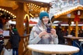 Beautiful young woman drinking hot punch, mulled wine on German Christmas market. Happy girl in winter clothes with Royalty Free Stock Photo
