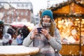 Beautiful young woman drinking hot punch, mulled wine on German Christmas market. Happy girl in winter clothes with Royalty Free Stock Photo